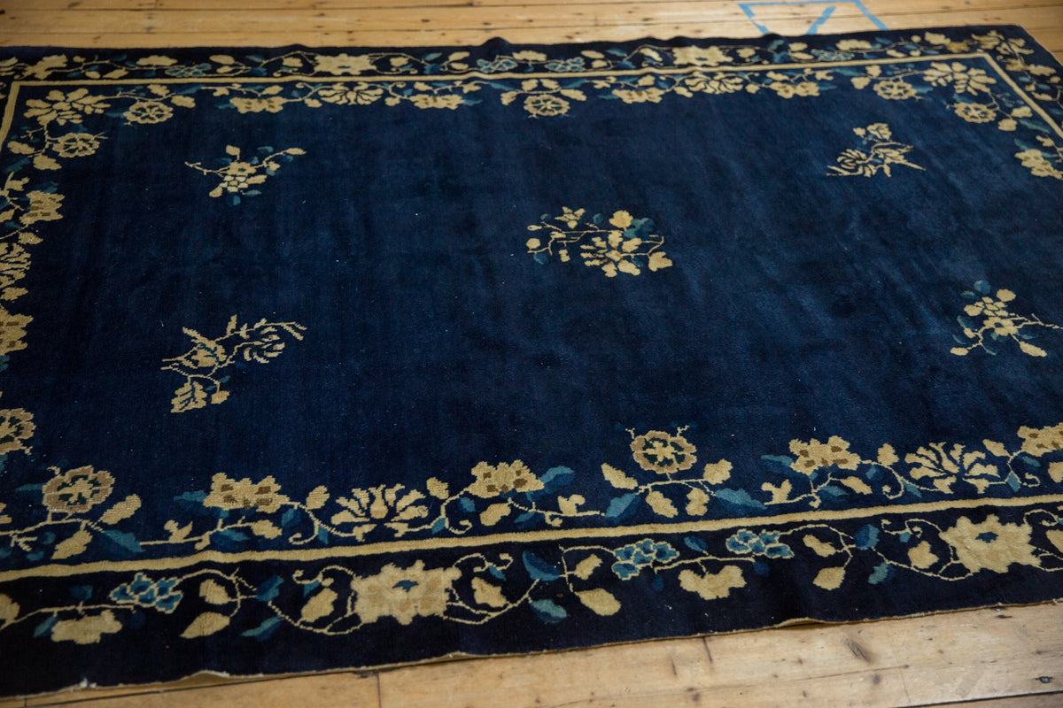 Navy blue rug with gold floral patterns on a wooden floor