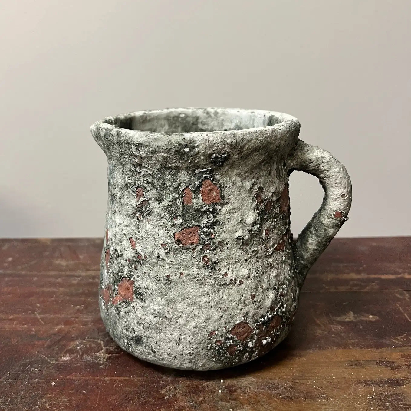 Vintage ceramic pitcher with a handle on a wooden surface