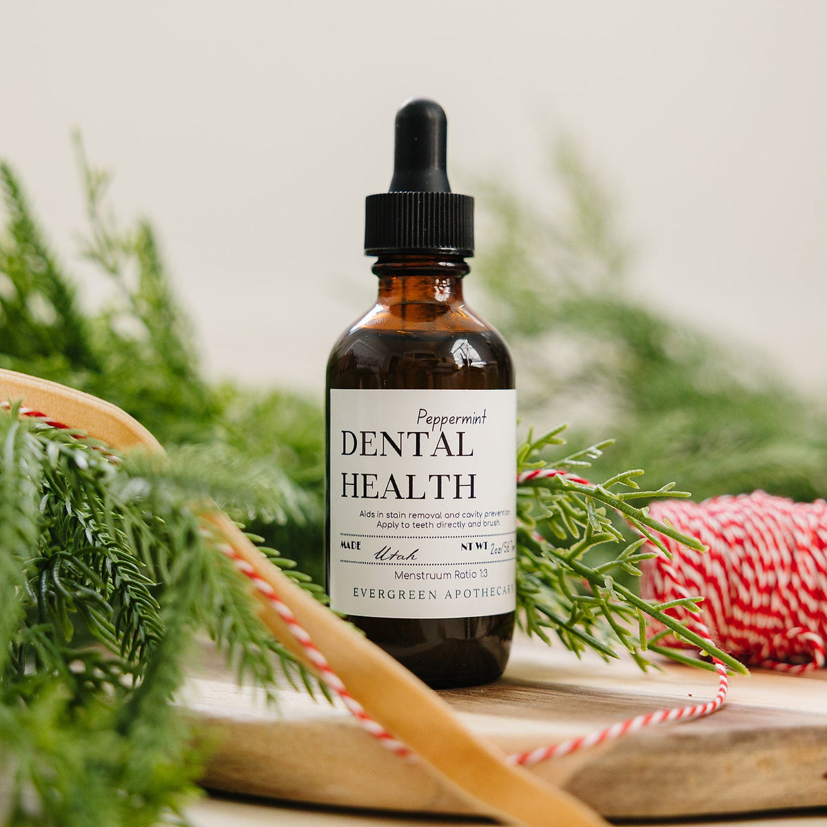 Bottle labeled 'Dental Health' with a dropper on a wooden surface with greenery