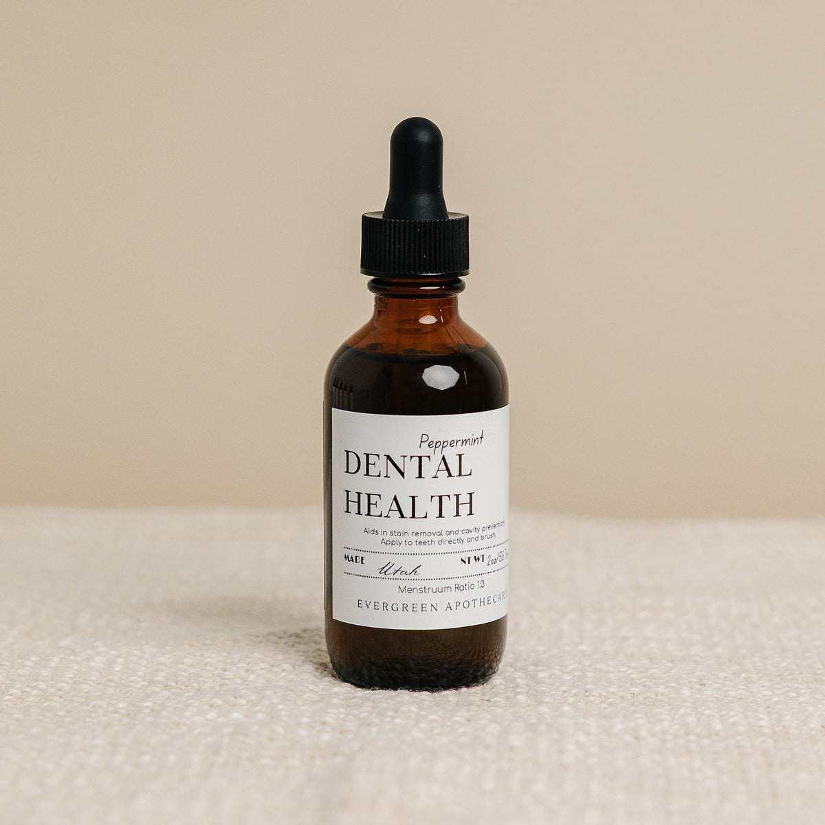 Bottle of dental health product with dropper on a beige background