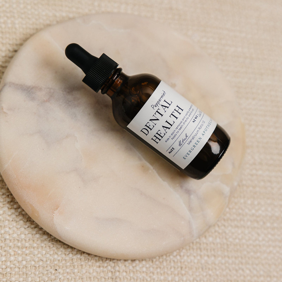 Bottle of dental health product with dropper on a marble coaster