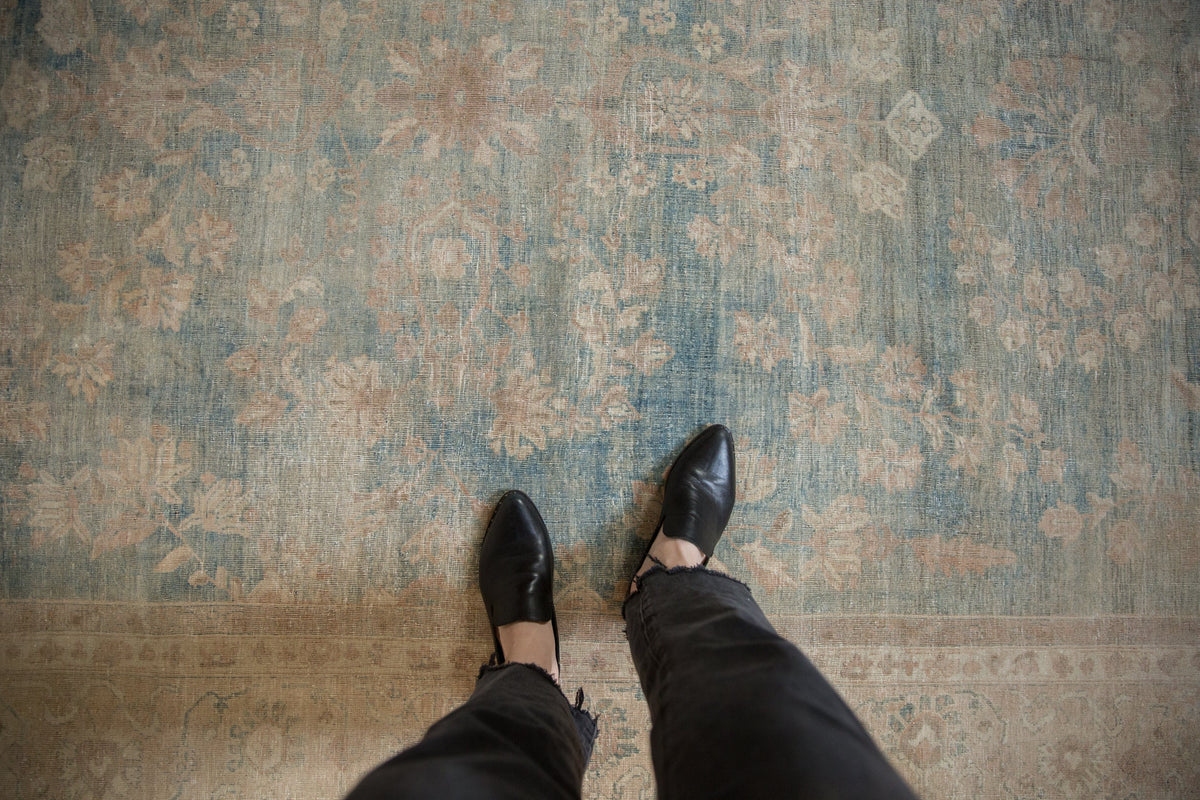 Person wearing black shoes and pants standing on a patterned rug.