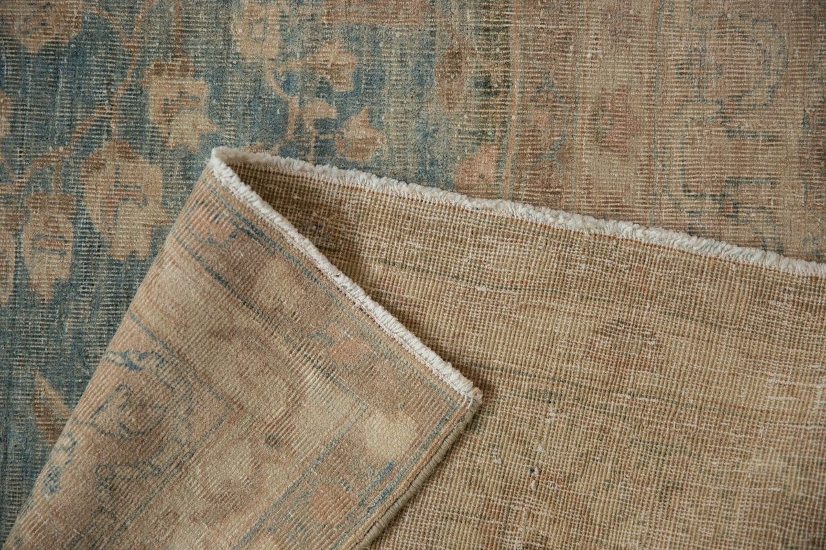 Close-up of a textured rug with floral patterns in brown and blue tones.