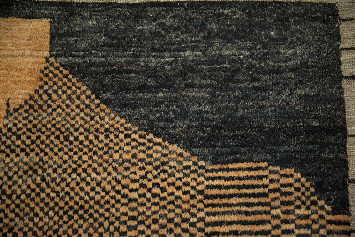 Close-up of a textured rug with geometric patterns in black, brown, and beige.