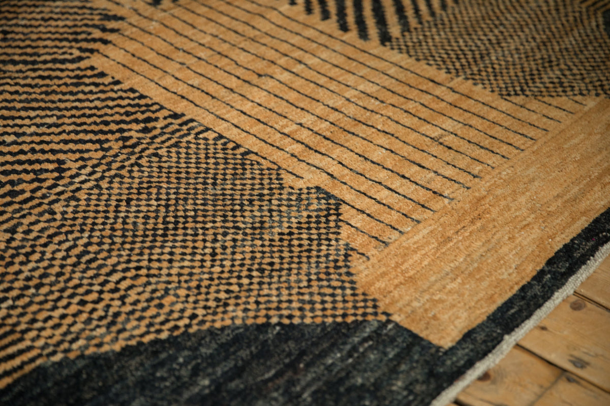 Close-up of a textured rug with a black and brown pattern on a wooden floor.