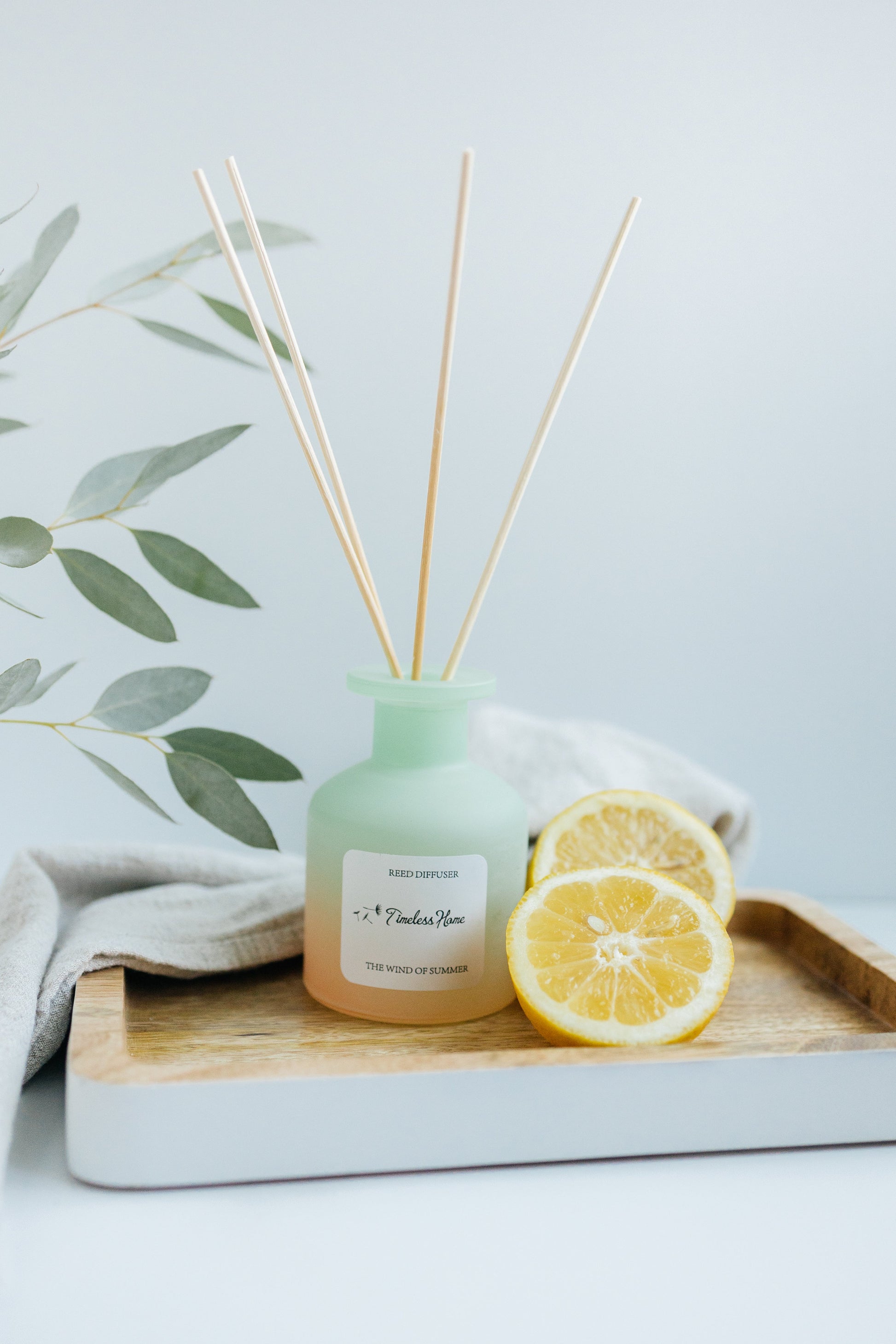 Reed diffuser with lemon slices and a cloth on a wooden board with a light background