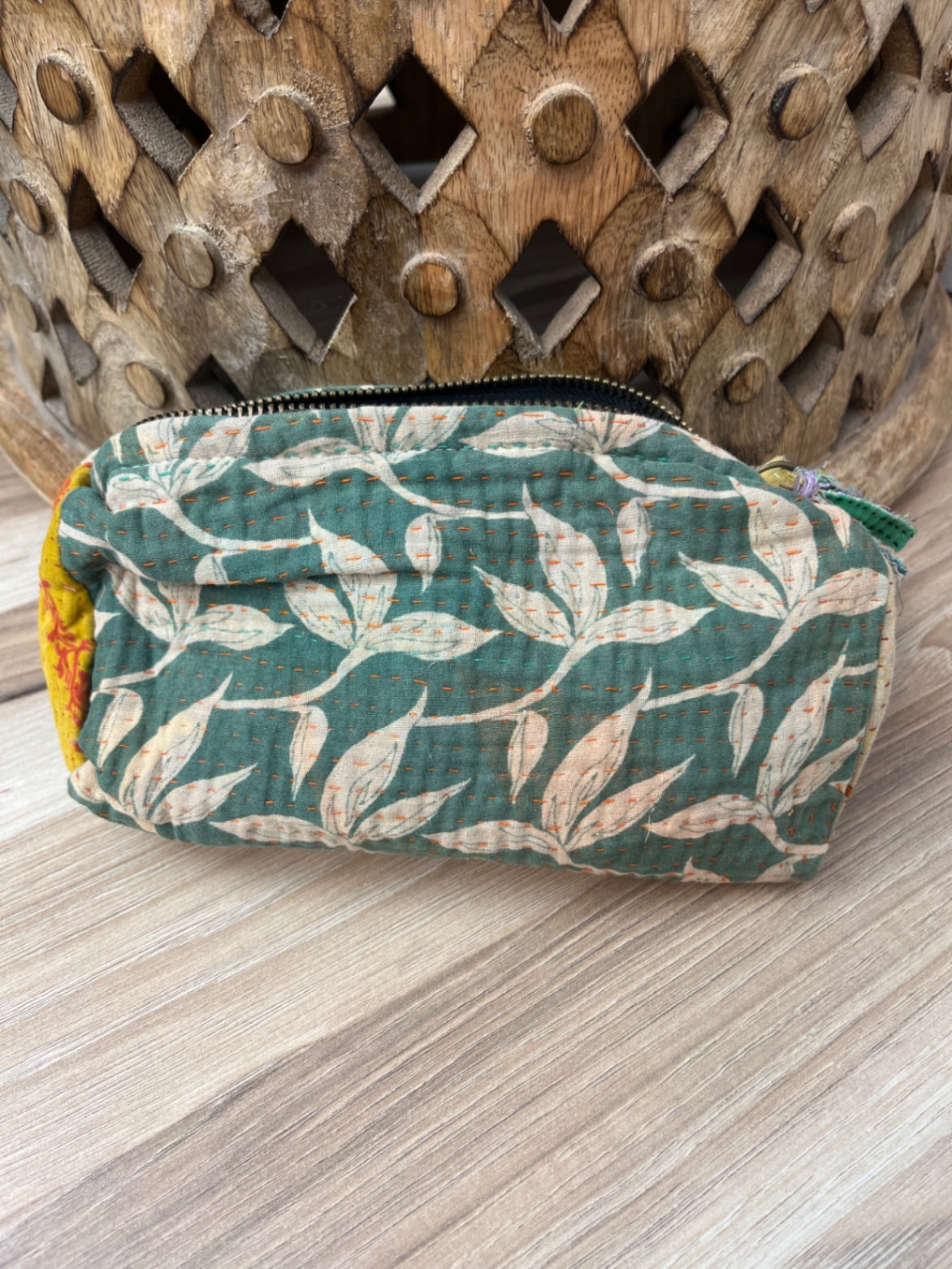 Fabric pouch with leaf pattern on a wooden surface