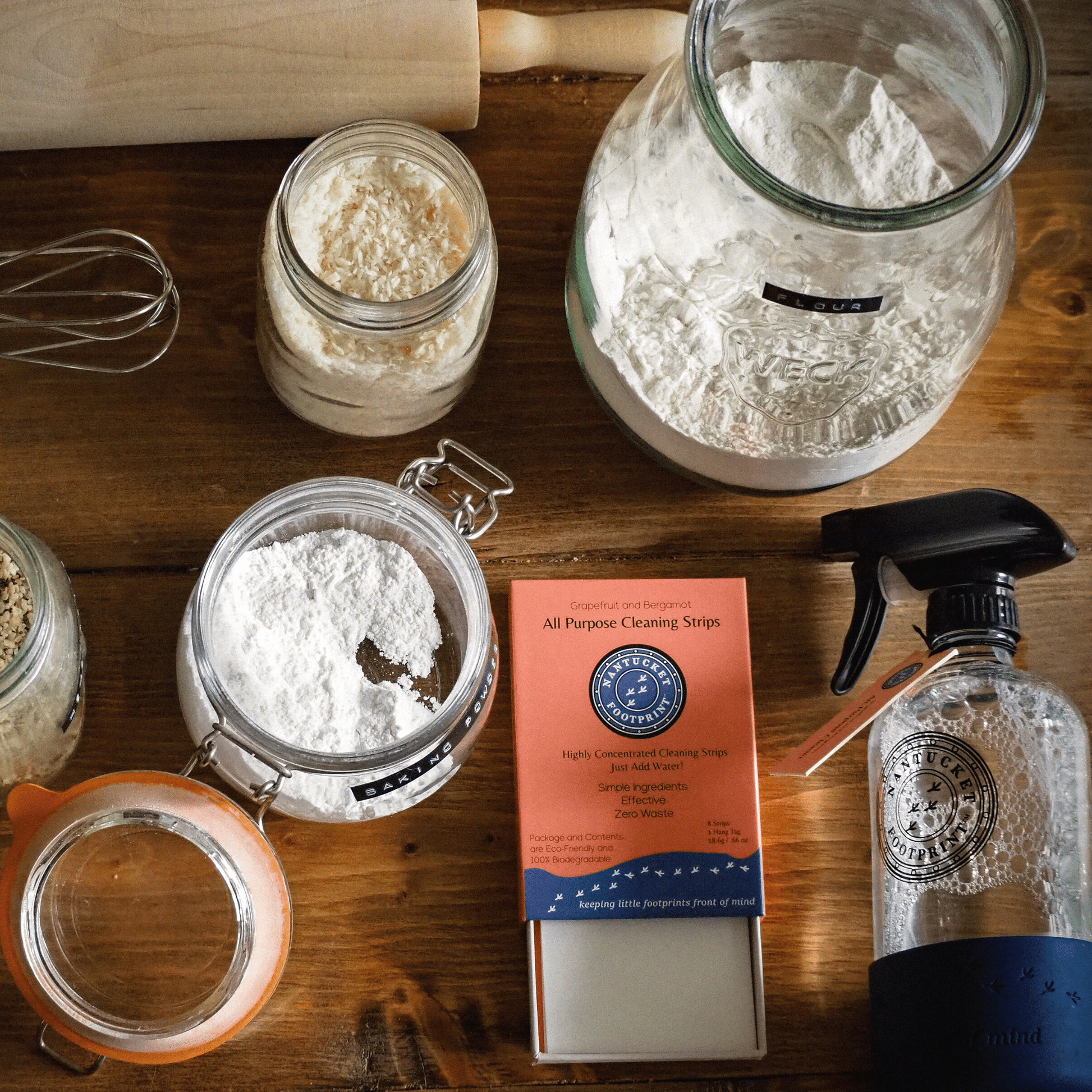 Various cleaning and kitchen items on a wooden surface, including jars of flour and cleaning strips.