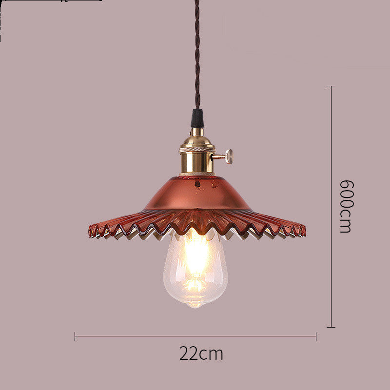 Vintage-style pendant light with copper finish and clear bulb on a plain background