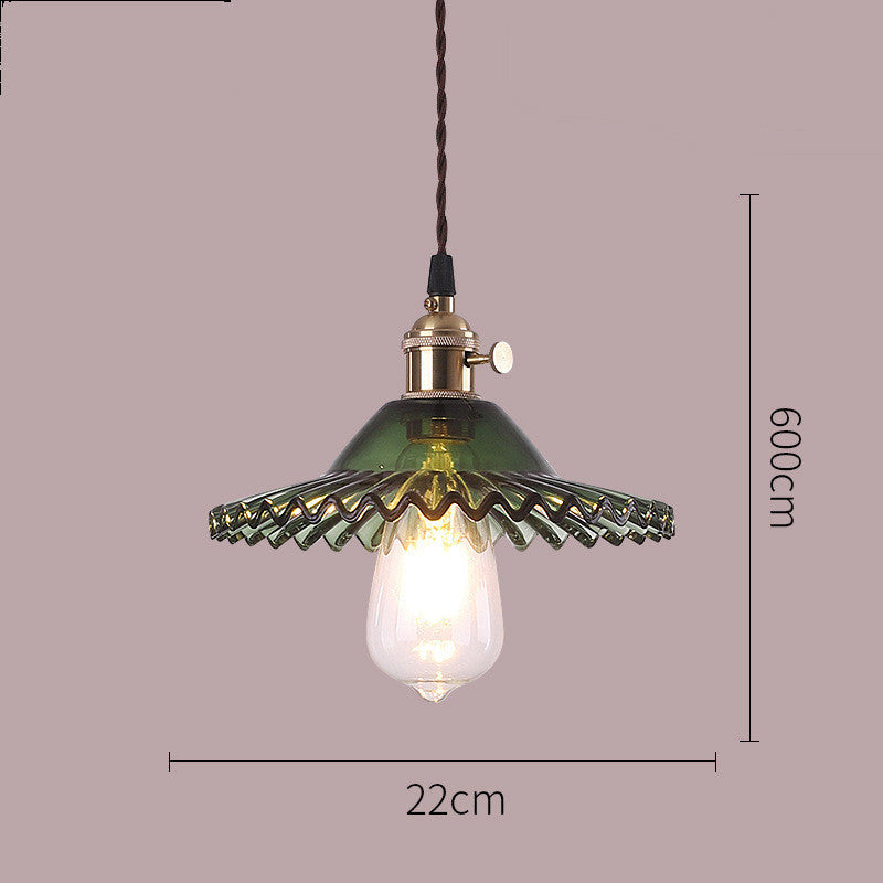 Pendant light with green glass shade and visible bulb on a gray background