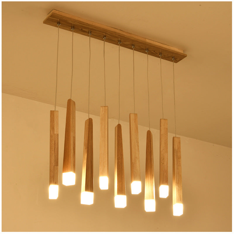 Wooden pendant light fixture with multiple cylindrical lights on a beige wall background