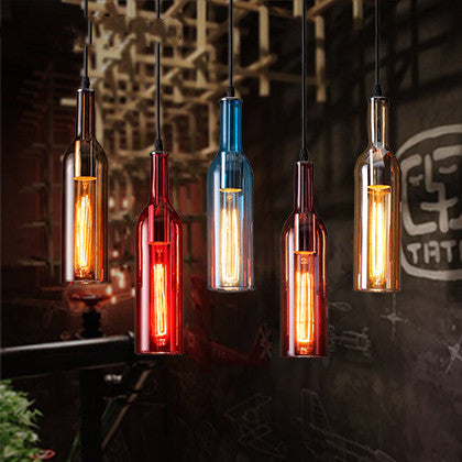 Five illuminated bottle pendant lights in various colors hanging against a dark background.