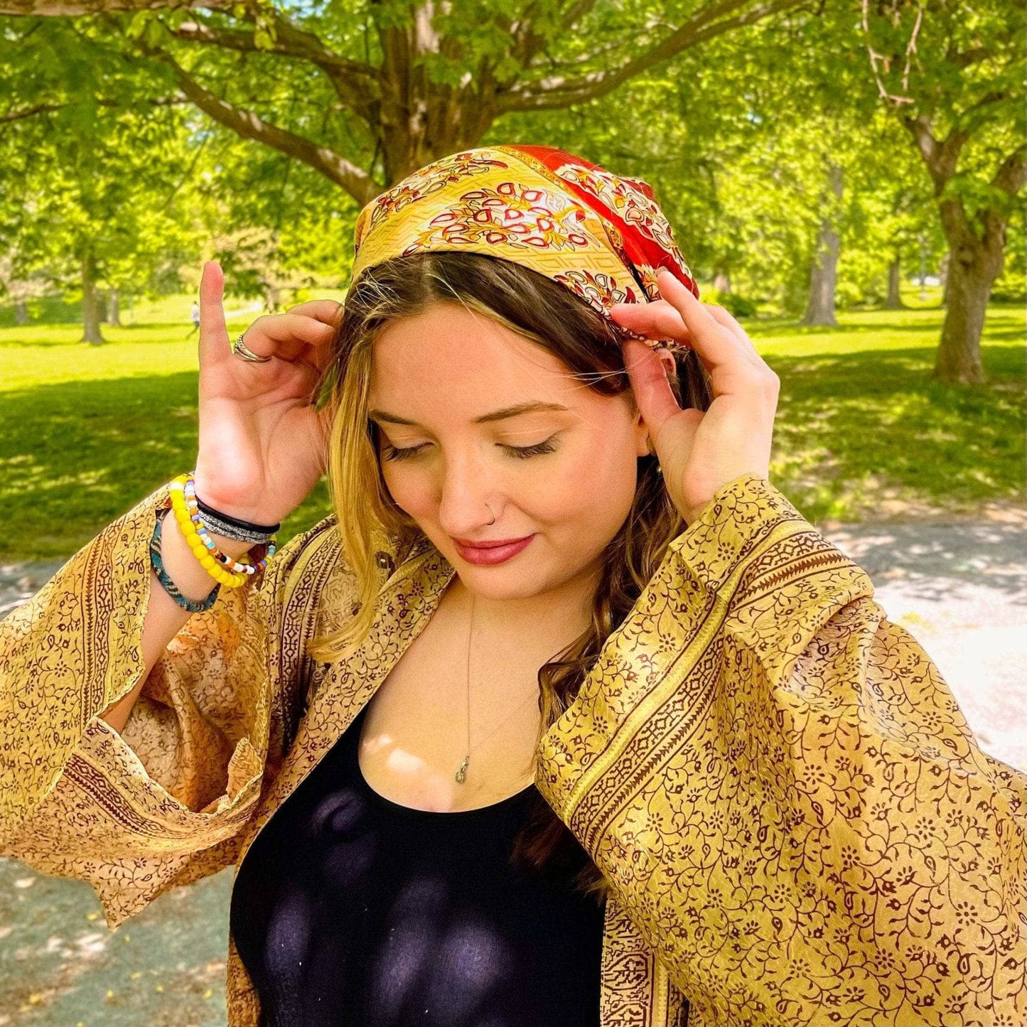 Woman adjusting a colorful headscarf in a park