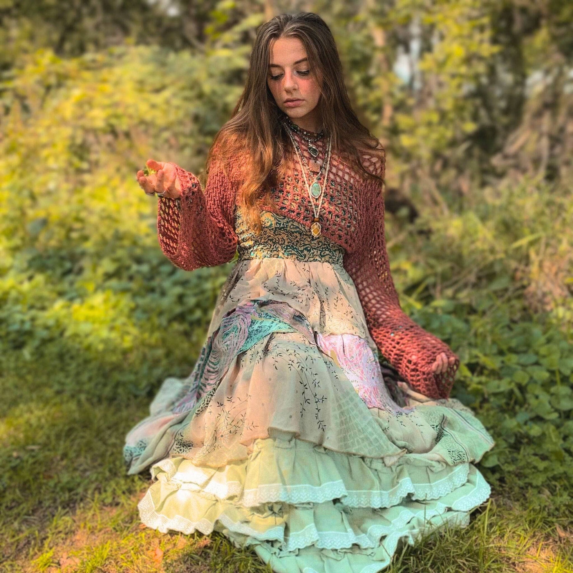 Woman in a colorful dress and sweater sitting in a natural setting