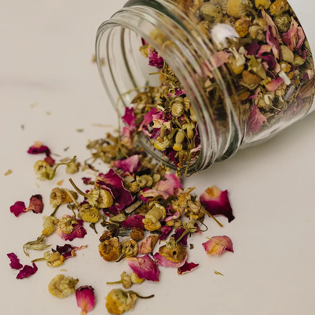 Glass jar filled with colorful dried flowers on a light background
