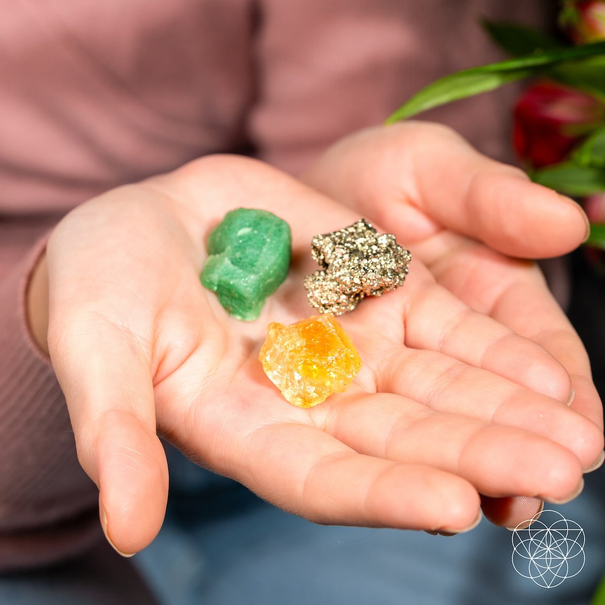 Three colorful crystals held in a person's palm with a blurred background