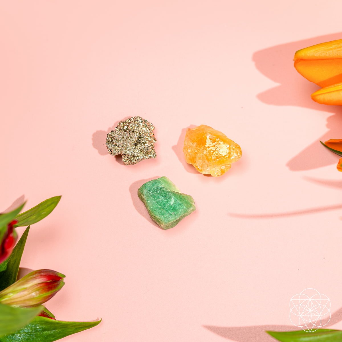 Three colorful crystal rocks on a pink background with tulips.