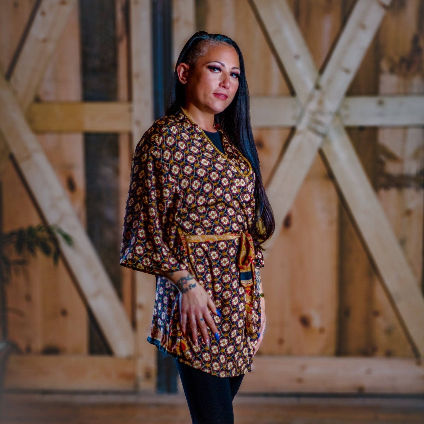 Woman wearing a patterned dress standing in front of wooden barn doors.