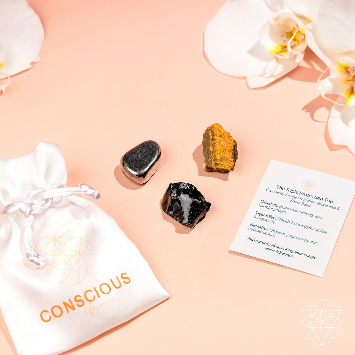 Three crystals on a pink surface with a 'Conscious' bag and an informational card.