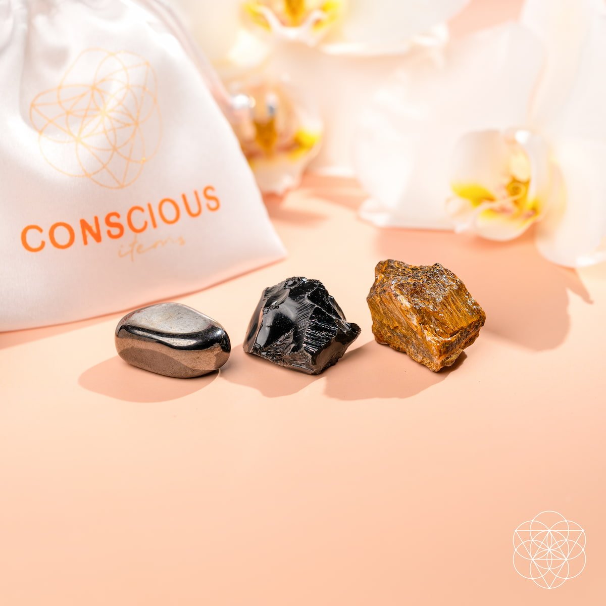 Three crystals on a pink surface with a 'Conscious' branded bag in the background.