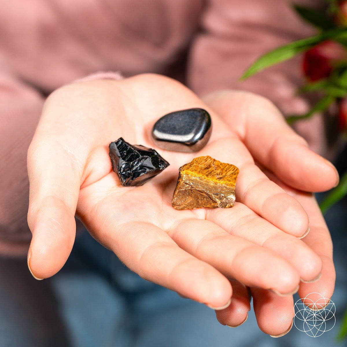 Three different colored stones held in a person's palm with a blurred background