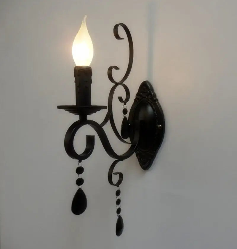 Decorative black wall sconce with a lit bulb on a white wall
